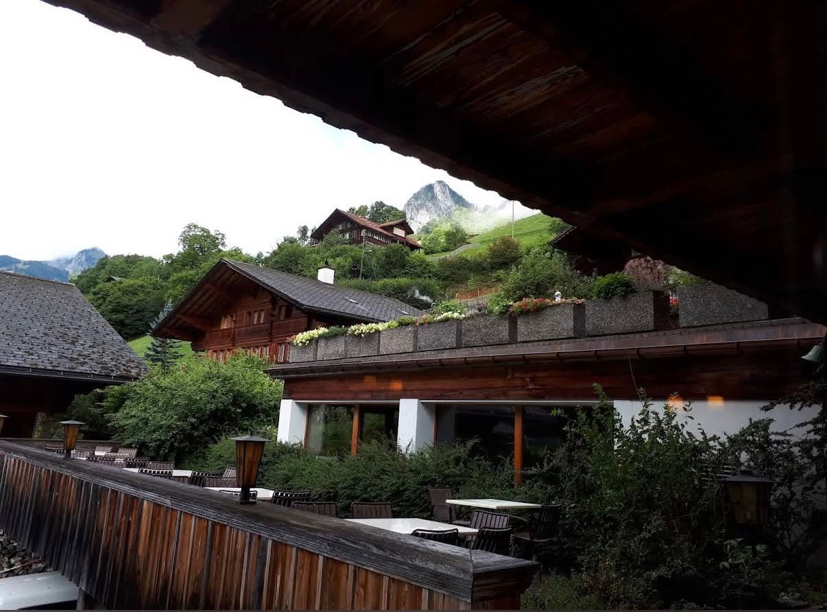 Outdoor tables on the hotel terrace, surrounded by timber buildings and mountain greenery