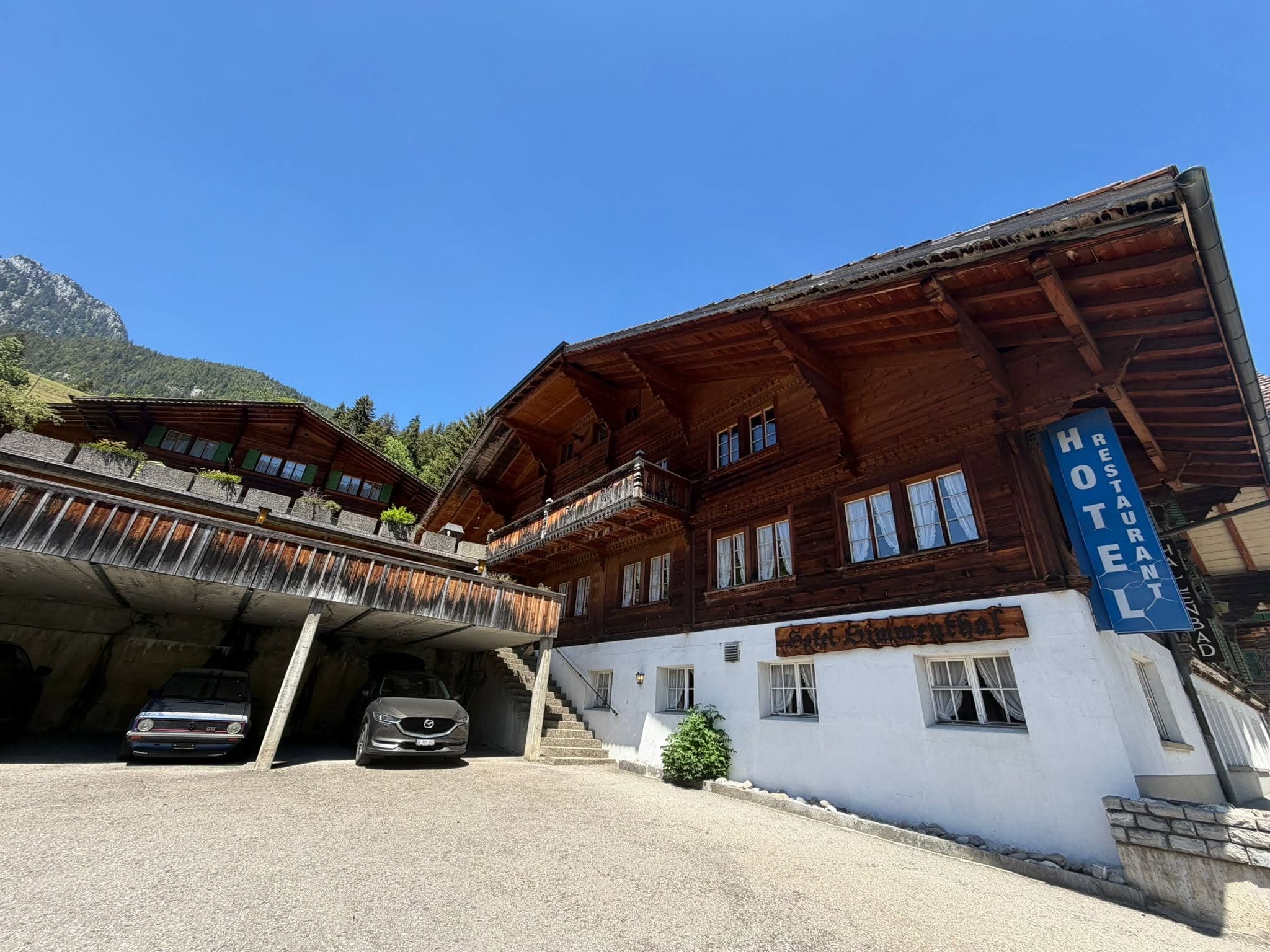 Traditional wooden hotel facade with carved eaves, a balcony and the hotel sign