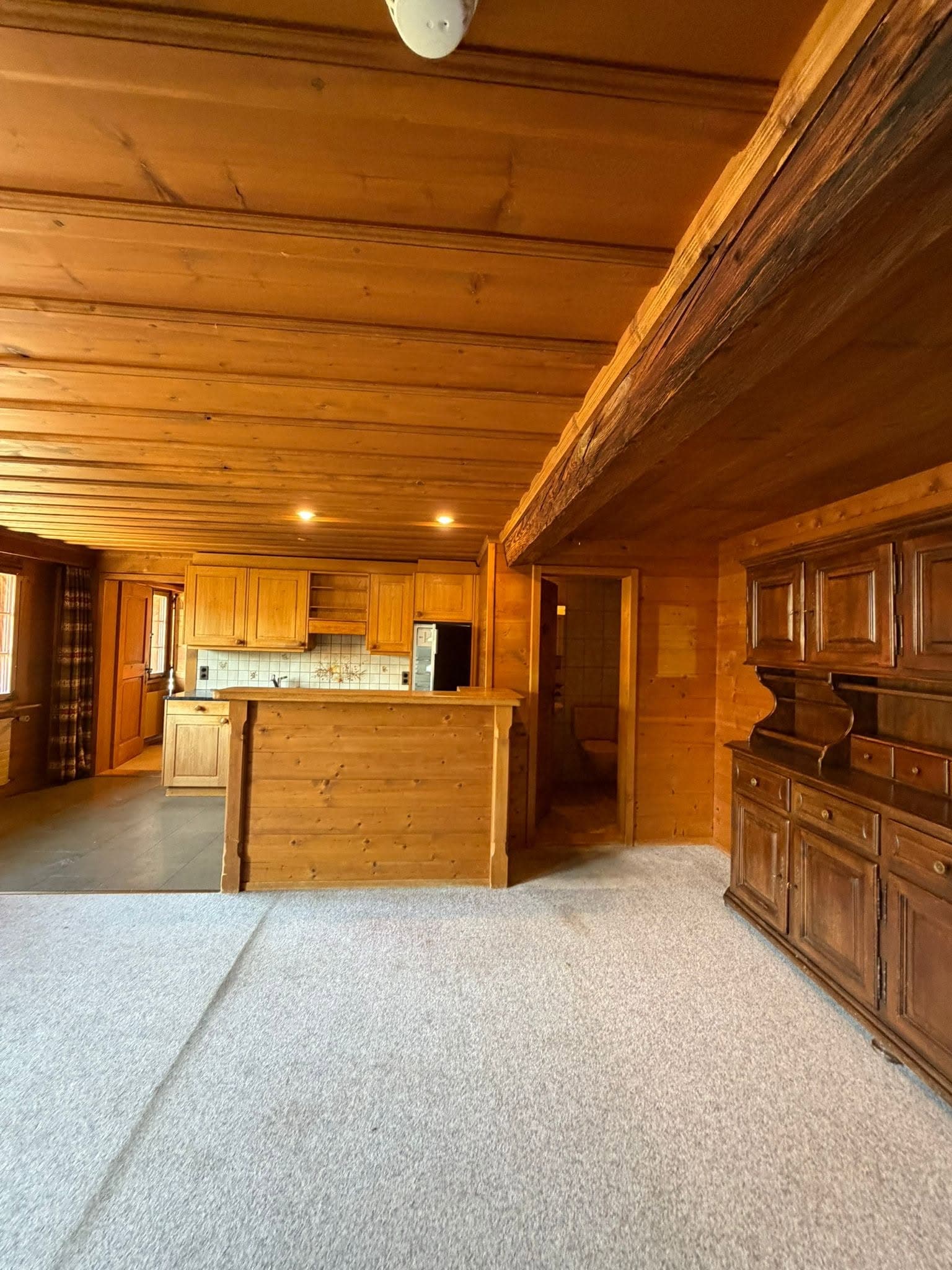 Wood-panelled interior with an exposed beam, built-in cupboards and a counter